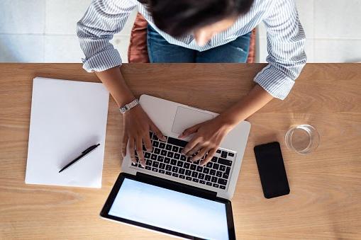 Woman typing on a laptop.